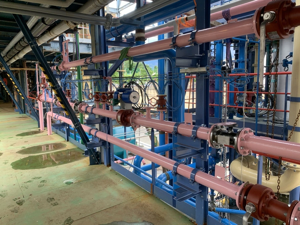 Tuyauterie industrielle dans un bâtiment industriel de type usine avec des tuyaux bleus et roses